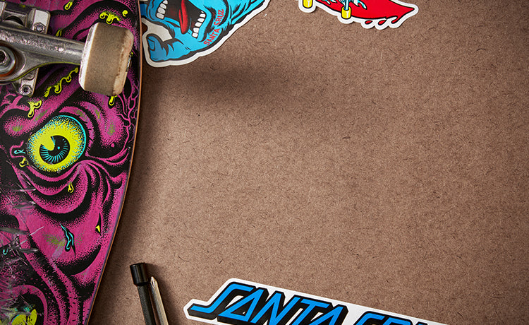 Santa Cruz skateboard deck sits with colorful Santa Cruz stickers